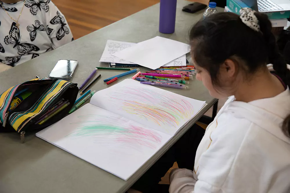 Happy NDIS participant drawing at table