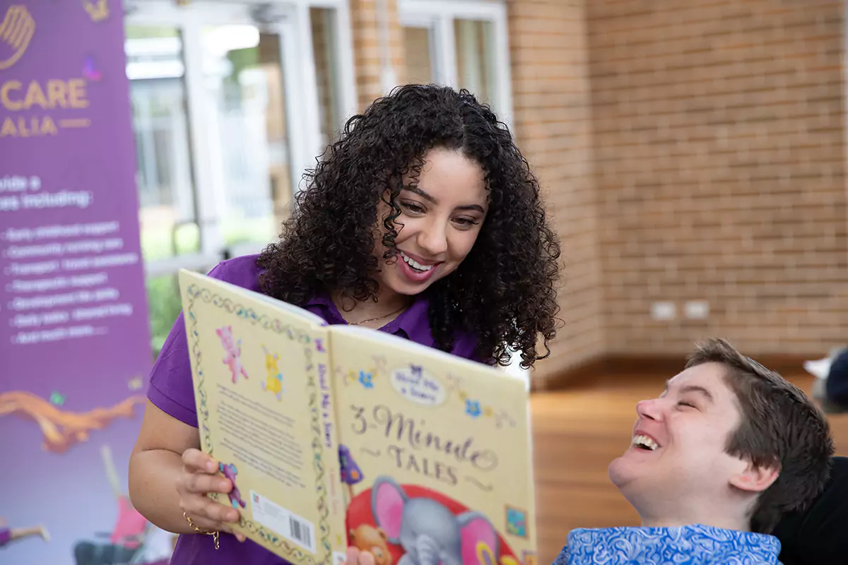 Divine Care Australia support worker reading a book to NDIS participant