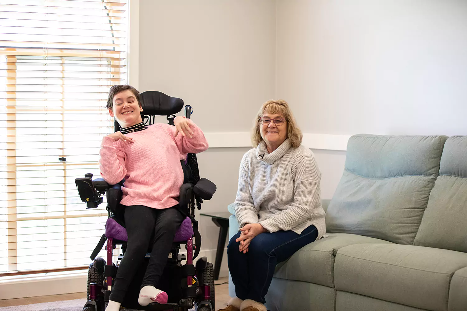 Happy disabled woman in wheelchair smiling at camera with happy woman sitting next to them